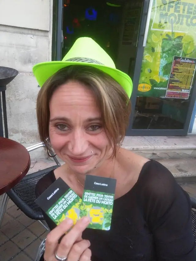 Une participante coiffée du panama vert fluo de la Fête du Mojito, son pass à la main